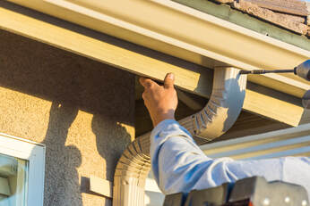 Man installing downspout onto a 5 inch K style seamless gutter system